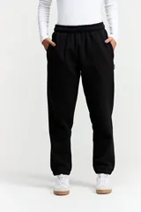 Pantalón tipo jogger de tiro medio con cintura elastizada y puños en los tobillos. Confeccionado en tejido de algodón y poliéster, presenta un diseño liso y holgado.