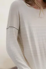 Sweater color crema con rayas horizontales y mangas largas.