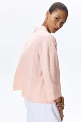 Camisa de corte holgado confeccionada en mezcla de lino y viscosa, de color rosado. Presenta cuello abierto, cierre frontal con botones, hombros caídos y mangas tres cuartos.