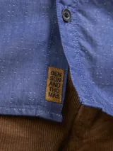 Camisa azul de manga larga con bolsillo en el pecho.