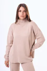 Buzo tejido de punto en color beige, con cuello alto, mangas largas con puños ajustados y corte holgado.
