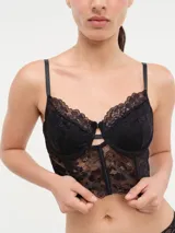 Bustier de encaje negro con diseño tipo corset, copas con aros, breteles finos ajustables y cierre frontal con detalle de abertura.