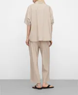 Camisa oversize color beige con diseño de microdibujo a cuadros, cuello italiano, mangas cortas japonesas y cierre frontal con botones.
