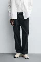 Pantalón de corte relaxed fit confeccionado en mezcla de algodón y modal. Presenta cintura con pliegues frontales, bolsillos laterales y bolsillos traseros con solapa. Cierre frontal con cremallera y botón.