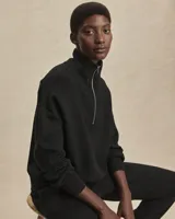 Buzo deportivo negro de corte oversize, confeccionado en tejido DoubleSoft®. Presenta cuello con paneles, media cremallera metálica y puños y bajo amplios.