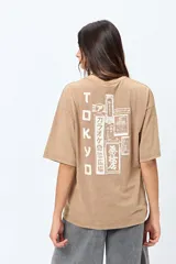 Remera negra de corte amplio con mangas cortas y cuello redondo. Presenta un pequeño estampado rectangular en el pecho y un estampado grande en la espalda con motivos japoneses.