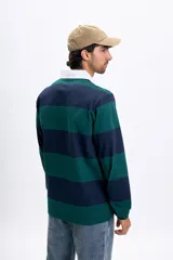 Remera polo de manga larga a rayas horizontales en azul marino y verde oscuro, con cuello blanco y tapeta de botones. Incluye la estampa "1979" en el pecho.