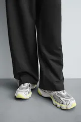 Zapatilla deportiva tipo running color blanco hueso con detalles en azul marino y amarillo flúor.