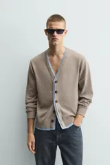 Cárdigan de punto con cuello en pico y manga larga. Presenta un diseño de ajuste relajado con cierre frontal de botones y acabados en rib con efecto doble en color azul a contraste sobre la base color topo.