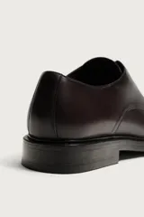 Zapato de cordones tipo blucher color marrón oscuro, confeccionado en piel con horma redonda y suela con ligero tacón.