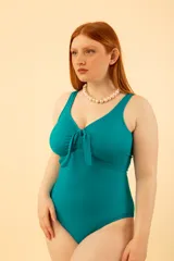 Malla entera color turquesa con nudo en el escote. Tiene gran contención y cobertura del busto, con bolsillo interno para colocar copa removible o prótesis externa. Confeccionada con tela que contiene fibra LYCRA® XTRA LIFE™.