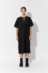 Vestido largo de manga corta y corte oversize, confeccionado en tejido con textura. Presenta cuello redondo y un parche decorativo en la parte posterior.
