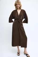 Vestido midi de tejido satinado color marrón, con escote en pico, manga corta y detalle de nudo frontal que genera un efecto drapeado.