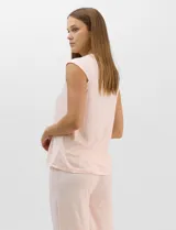 Pijama compuesto por remera sin mangas con escote redondo, botones frontales y detalle de puntilla, acompañado de un pantalón capri con cintura elástica. Presenta un estampado floral en tonos rosados sobre base gris.