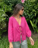 Blusa fucsia de lino con escote en V y mangas largas abullonadas con puños elásticos. Se cierra con lazos en la parte delantera.