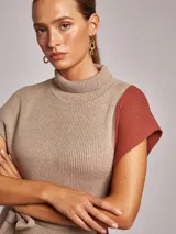 Vestido midi de tejido acanalado con cuello alto, sin mangas y diseño bicolor en tonos beige y terracota. Incluye un lazo ajustable en la cintura para entallar la silueta.
