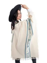 Poncho color crema con diseño de franjas verticales con motivos geométricos en color celeste y flecos en el borde inferior.