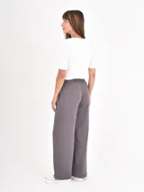 Pantalon de estilo deportivo en color gris oscuro, confeccionado en tejido de punto suave. Presenta un corte recto y holgado, cintura elástica con cordón ajustable y costuras verticales decorativas en el frente.