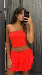 Minifalda de tiro bajo color naranja neón, con diseño de volados en capas y ajuste elástico en la cintura.