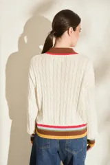 Buzo de punto azul marino con cuello polo blanco y detalles de rayas de colores en el cuello, los puños y el ruedo. Cuenta con cierre frontal parcial de botones y diseño tejido de ochos.