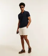 Polo de manga corta color azul marino con textura de malla, cuello y bordes de mangas en rib con detalles en contraste blanco. Cuenta con cierre frontal de botones.