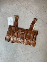 Top de diseño artesanal confeccionado en cuero genuino color cobre, compuesto por tiras rectangulares unidas mediante argollas metálicas. Presenta un diseño tipo crop top con breteles anchos.