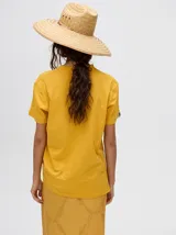 Remera de corte cuadrado y ajuste holgado, color verde oliva, con pequeño estampado gráfico de un velero en el pecho y etiqueta decorativa en la manga.