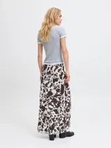 Pollera larga de corte recto confeccionada en tejido mesh con estampado animal print tipo vaca en tonos blanco y marrón oscuro. Presenta cintura elastizada y diseño fluido.