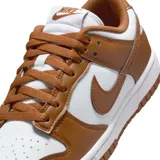 Championes Nike Dunk Low con diseño bicolor en blanco y marrón. Presentan una silueta clásica de perfil bajo, confeccionados en cuero con el icónico logo de la marca en los laterales, cierre de cordones y suela de goma resistente.