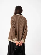 Cardigan tejido de punto con diseño a rayas verticales en tonos marrón y beige con hilo de lurex. Presenta mangas globo con puños ajustados y un corte holgado.