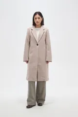 Tapado de corte recto con solapas clásicas y cierre frontal de un botón. Presenta mangas largas y bolsillos laterales integrados.