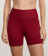 Bermuda deportiva femenina color bordó, tiro alto, confeccionada en microfibra. Presenta un recorte lateral contrastante de color rosado claro que recorre la pierna.