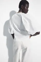 Camiseta blanca de corte slim fit con cuello redondo y mangas cortas abullonadas en tejido a tono.