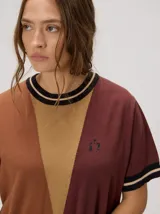 Vestido corto de punto tricolor, con diseño de bloques en tonos turquesa, celeste y azul marino. Presenta cuello redondo y puños con líneas en tonos tostado y blanco, además de un sutil bordado en el pecho.