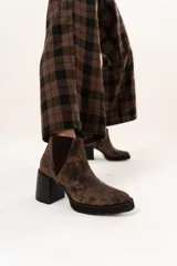 Bota tipo chelsea de cuero con acabado texturizado efecto desgastado en color chocolate. Presenta paneles laterales elásticos, suela de plataforma y taco cuadrado robusto en color negro.