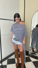 Vestido corto de dos piezas compuesto por una base strapless con frunces y acabado satinado, acompañada de una capa transparente desmontable de corte asimétrico.