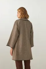 Tapado de largo medio abierto con cuello, confeccionado en lana fina sin teñir con detalles de terminación envivados en los bordes y mangas tres cuartos.