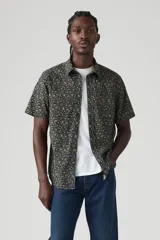 Camisa de manga corta con estampado floral en tonos azul, verde y amarillo. Tiene cuello clásico, cierre con botones y un bolsillo en el pecho.