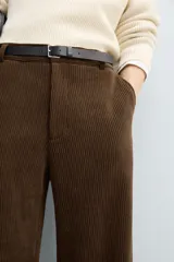 Pantalón de corte wide fit confeccionado en pana de algodón color marrón oscuro. Presenta bolsillos frontales, bolsillos traseros de vivo con botón y cierre frontal con cremallera y botón.