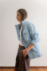 Campera reversible de estilo parka, color celeste, con diseño capitoneado con patrón de flores. Presenta ajuste elástico en la cintura, cuello alto y mangas largas. Incluye parche de marca en la parte superior de la espalda.