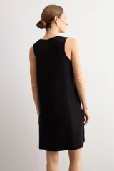 Vestido corto negro sin mangas, de corte recto y escote redondo, con detalles de tejido calado en el ruedo.
