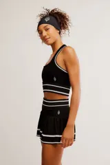 Conjunto deportivo compuesto por un top halter y una pollera pantalón de color blanco con líneas horizontales verdes.
