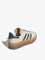 Zapatillas Adidas Gazelle Bold para mujer. Diseño clásico en gamuza color beige con las tres tiras laterales en azul marino. Suela de goma apilada color caramelo.