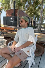 Remera tejida color crudo con cuello redondo con borde verde, mangas cortas y bolsillo en el pecho. Corte holgado.