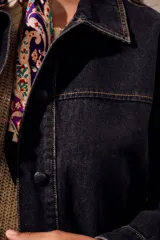 Campera oversize de denim negro, con cuello camisero, cierre frontal con botones y bolsillos ojal.