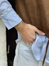 Brazalete ajustable de bronce, compuesto por múltiples aros finos.