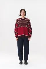 Buzo de tejido de punto con diseño geométrico y combinación de colores en contraste. Presenta cuello redondo, mangas largas y corte oversized.