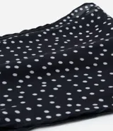 Pañuelo triangular de satén negro con lunares blancos.