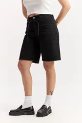 Bermuda larga de jean negro, de corte recto y tiro alto, con largo por encima de la rodilla. Cuenta con un lazo ajustable en la cintura y detalles desflecados en el ruedo.