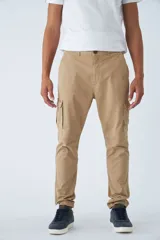 Pantalón cargo de hombre con fit slim, confeccionado en una mezcla de algodón y elastano. Presenta cierre de cremallera y botón, bolsillos laterales tipo cargo, pasa cinto y terminación con puños elásticos en los tobillos.